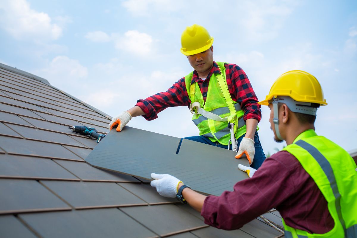 Two men in hard hats safely working on a roof, demonstrating proper heavy equipment access procedures.
