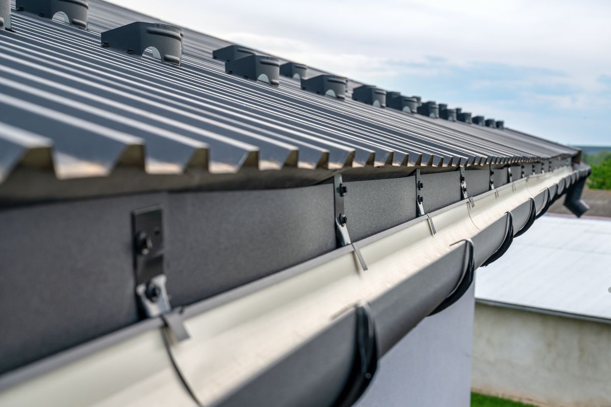  Close-up of a metal roof gutter, highlighting effective drainage for long-term flat roof health.